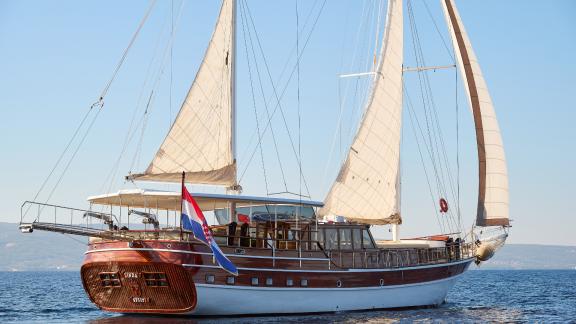 Die traditionelle Gulet Linda vor der Küste von Split, Kroatien, mit weißen Segeln und hölzernem Rumpf.